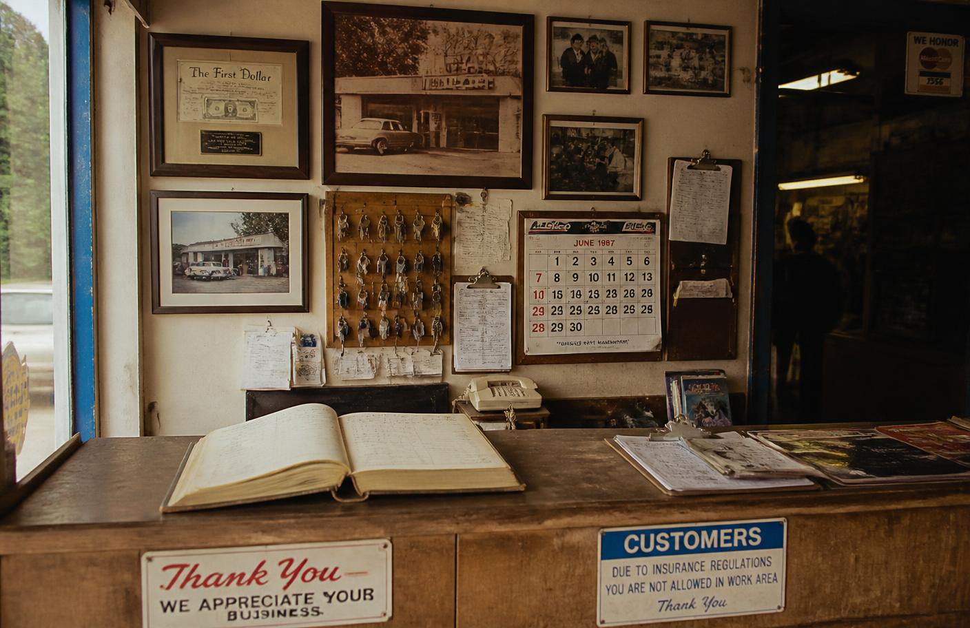 The front counter at Sergio's Auto Electric with the service ledger and decades of photographs on the wall